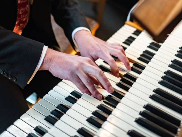 Nahaufnahme der Hände eines Organisten beim Spielen auf einer Orgel.